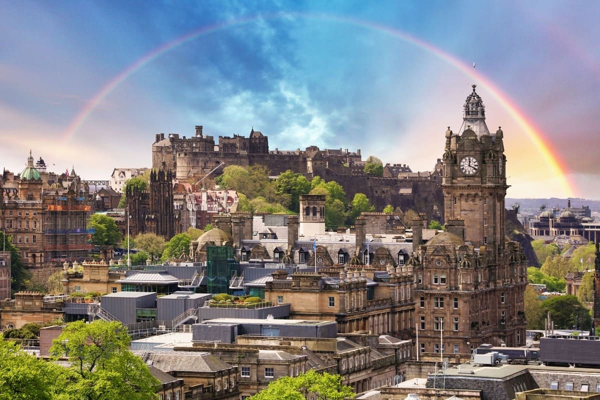 A complete rainbow arcs over Edinburgh Castle and the Old Town rooftops after a summer rain shower
